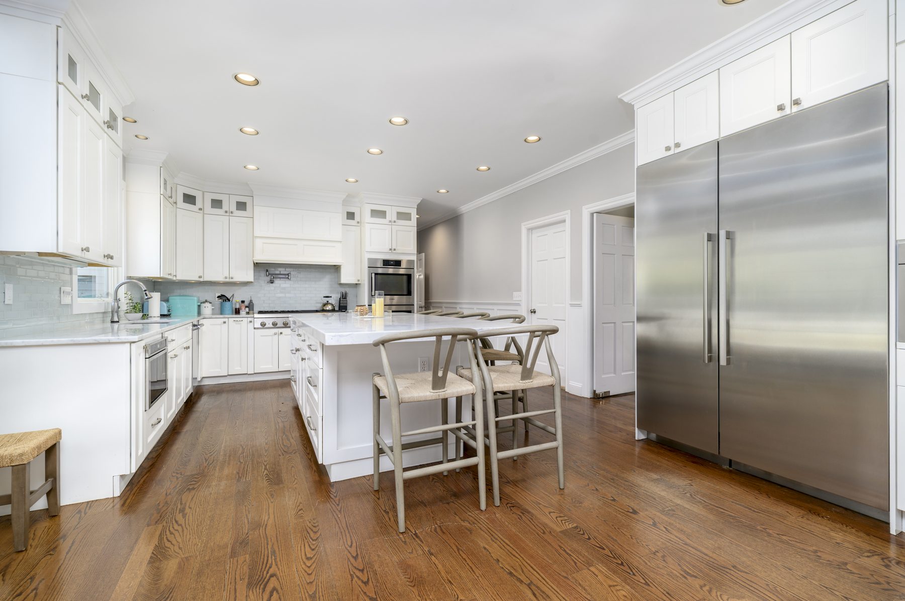 Bright kitchen with marble island, white cabinetry, and Sub-Zero refrigeration