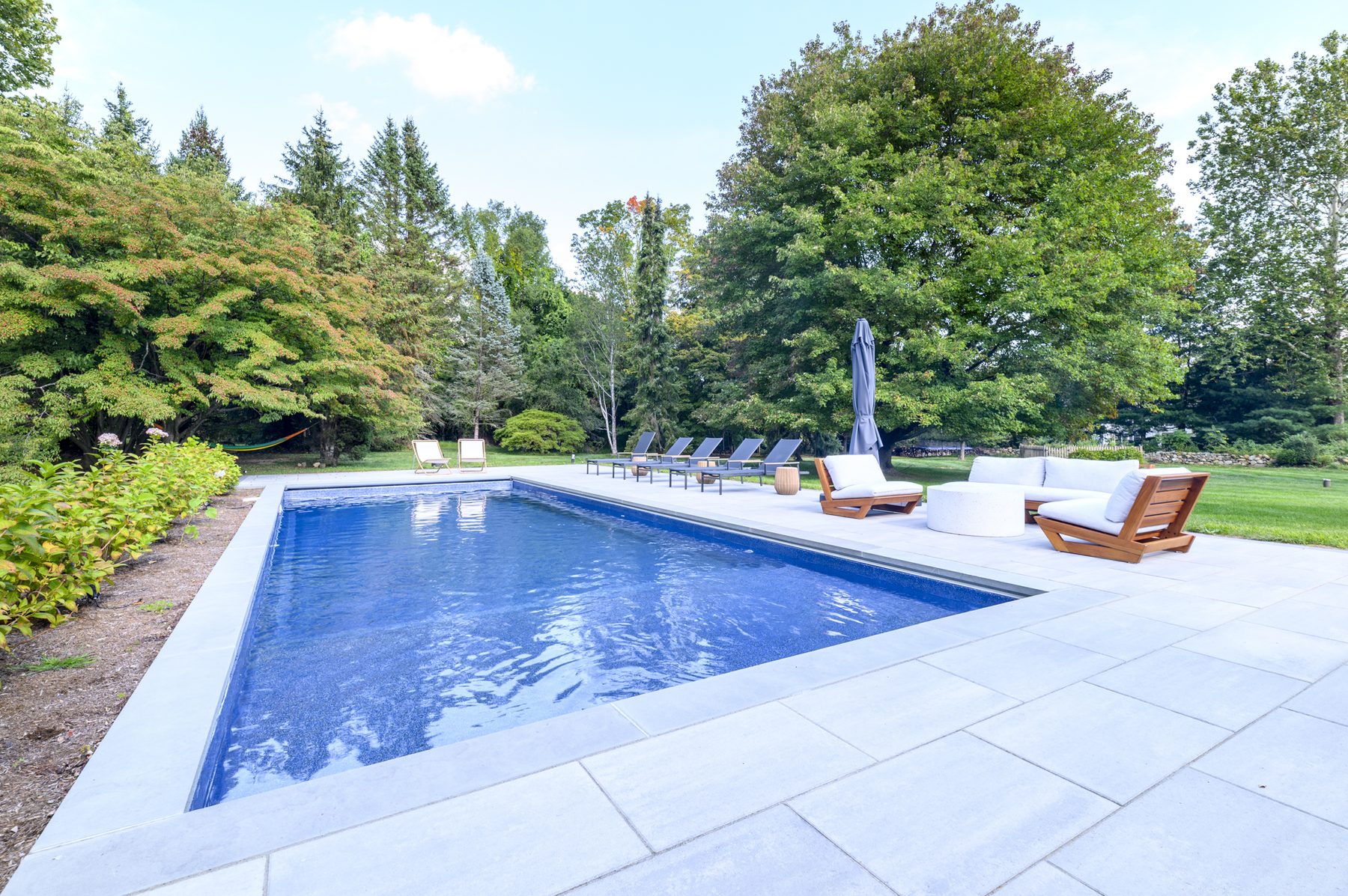 Saltwater pool with lounge chairs and woodland backdrop